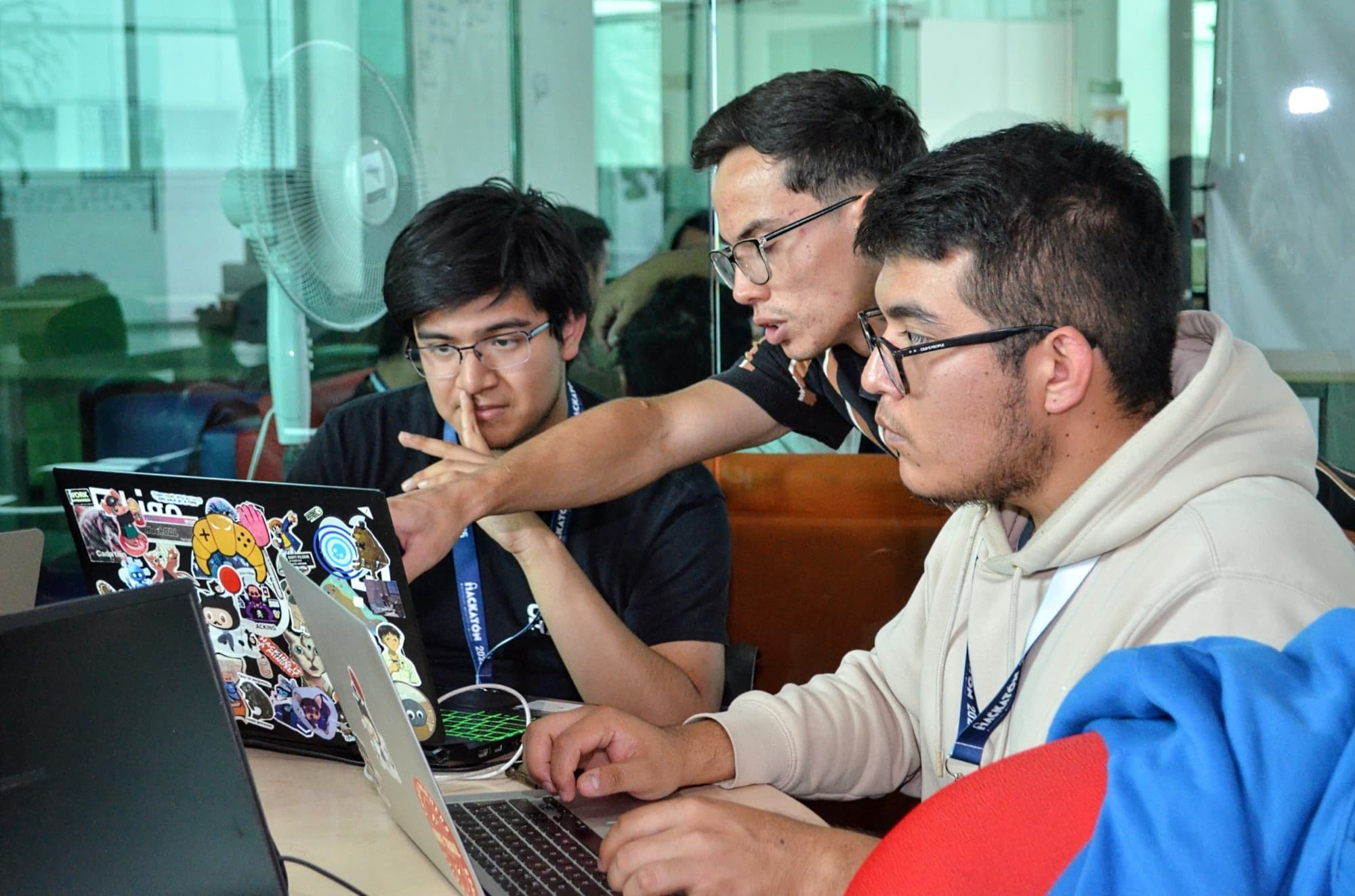 Three students work side by side, focused on their laptops.