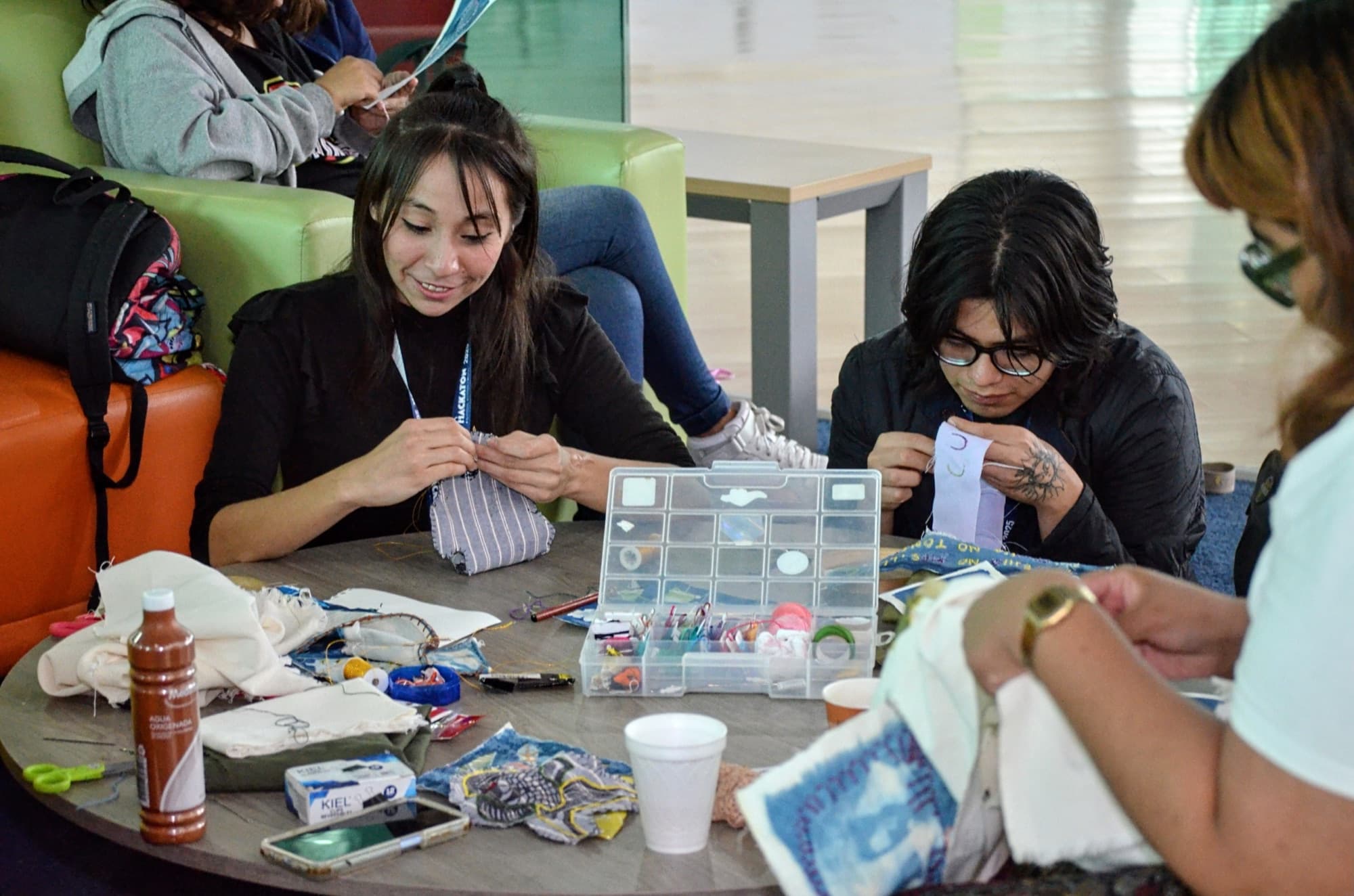 Two students assemble a prototype from materials and a box of parts on the table.